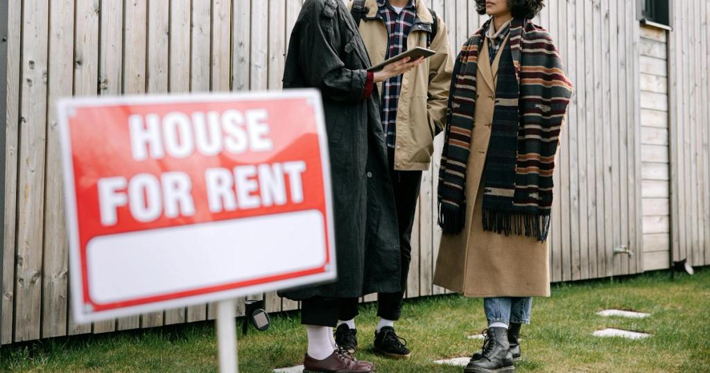 An interracial couple meets with a real estate agent to inquire about a house for rent.
