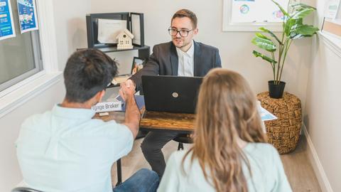 Men and woman discussing mortgage with broker in a modern office setting.