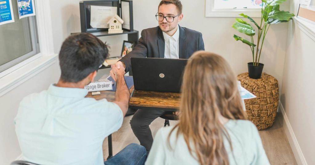 Men and woman discussing mortgage with broker in a modern office setting.