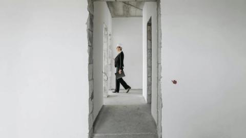 Professional woman in formal attire inspects an unfinished construction site. Ideal for real estate and construction themes.