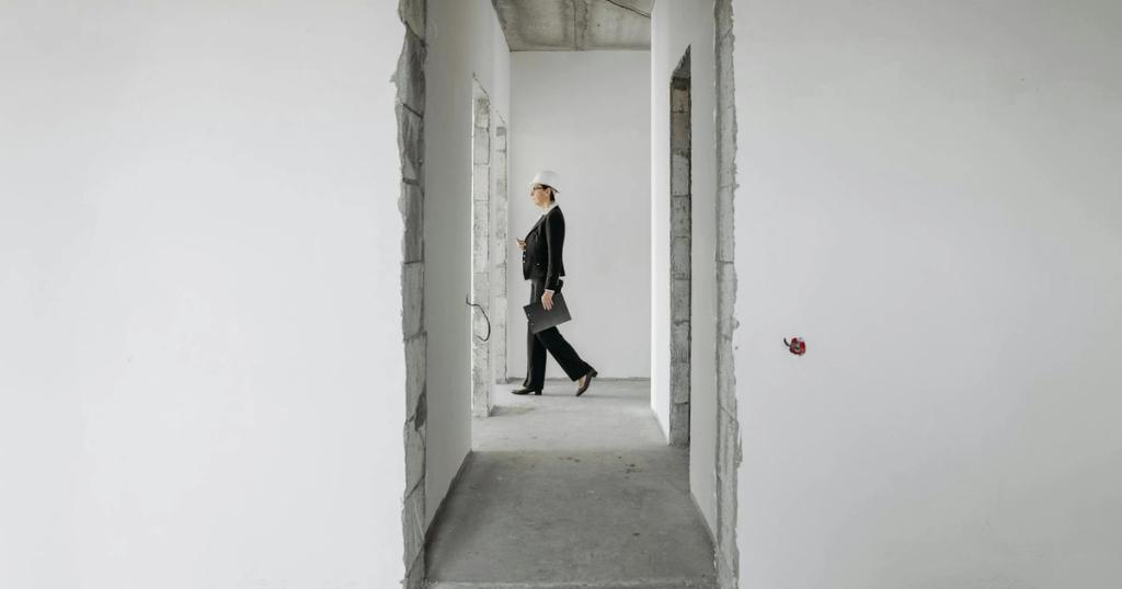 Professional woman in formal attire inspects an unfinished construction site. Ideal for real estate and construction themes.