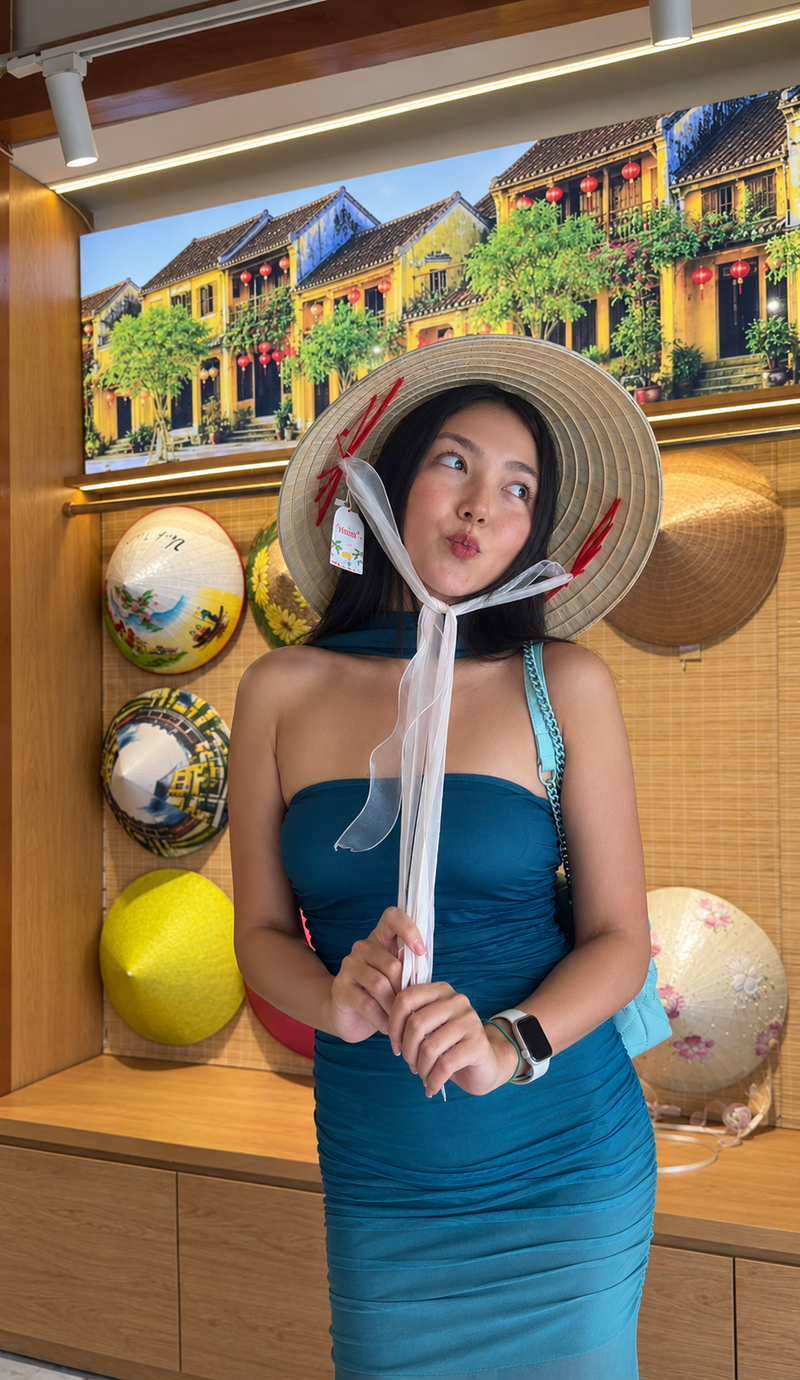 Amanda in a conical hat in a souvenir shop with painted hats on the wall