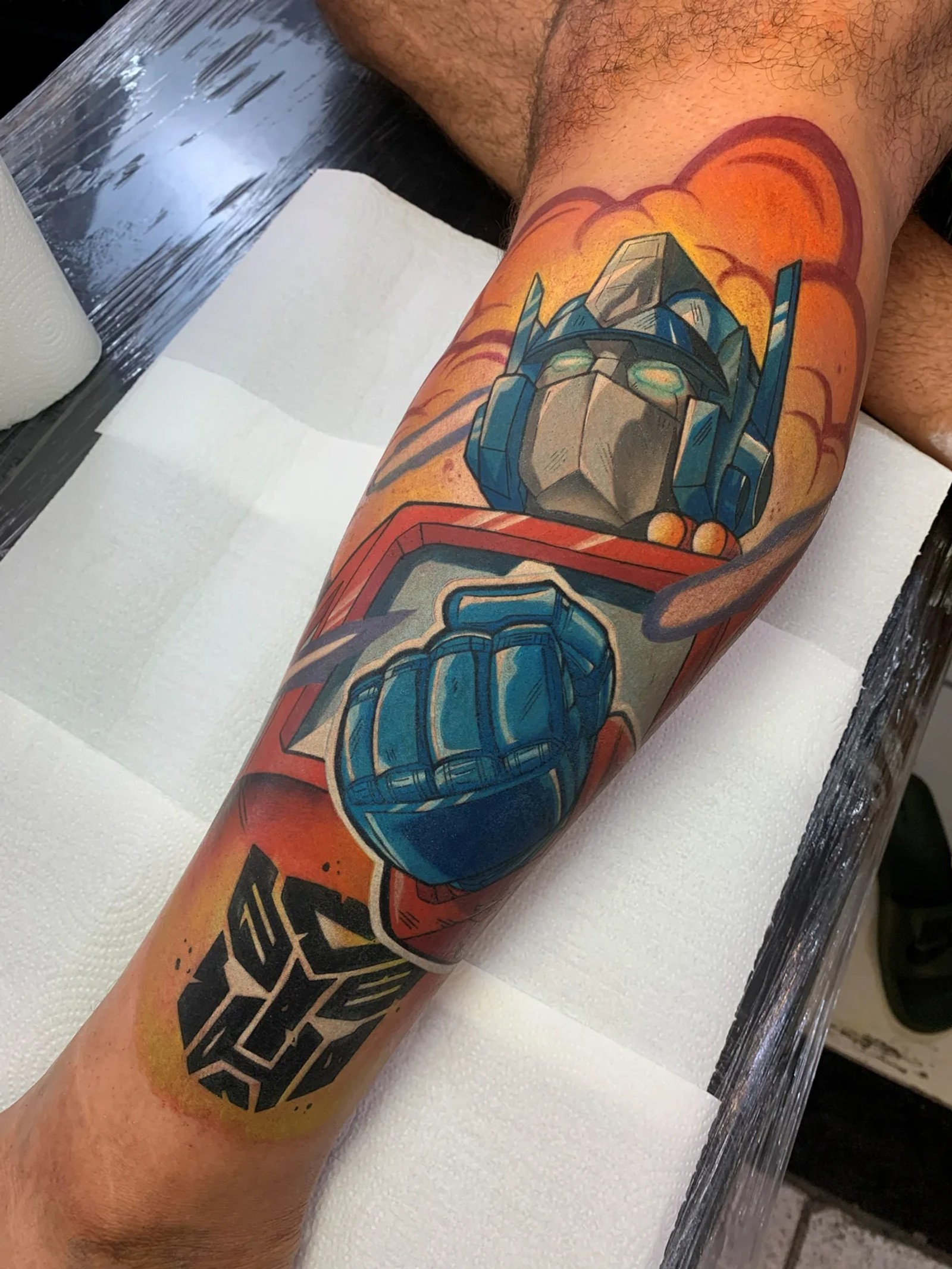 Tatuagem colorida do Optimus Prime, de Transformers, na perna