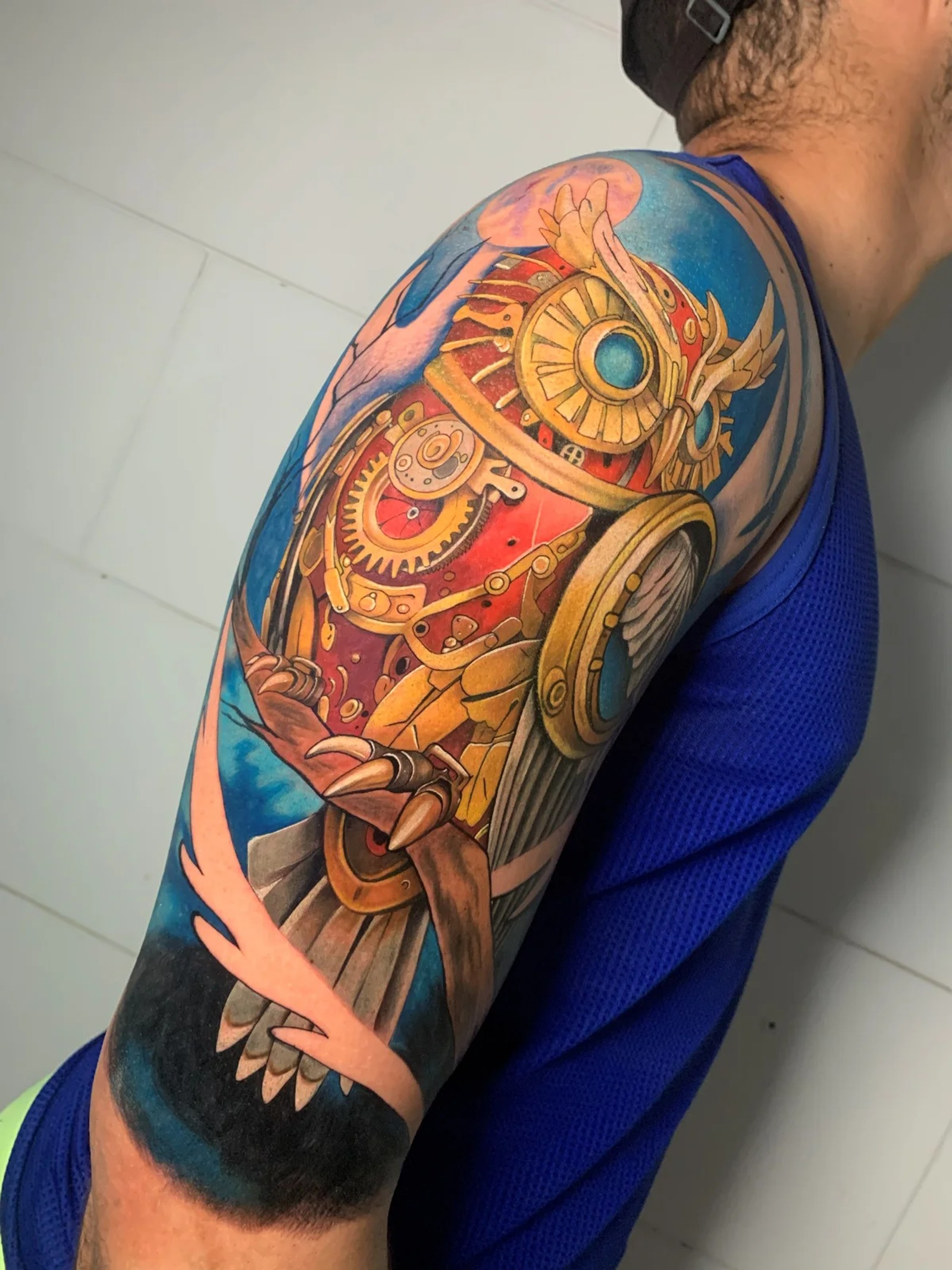 Tatuagem colorida ornamental com engrenagens no ombro
