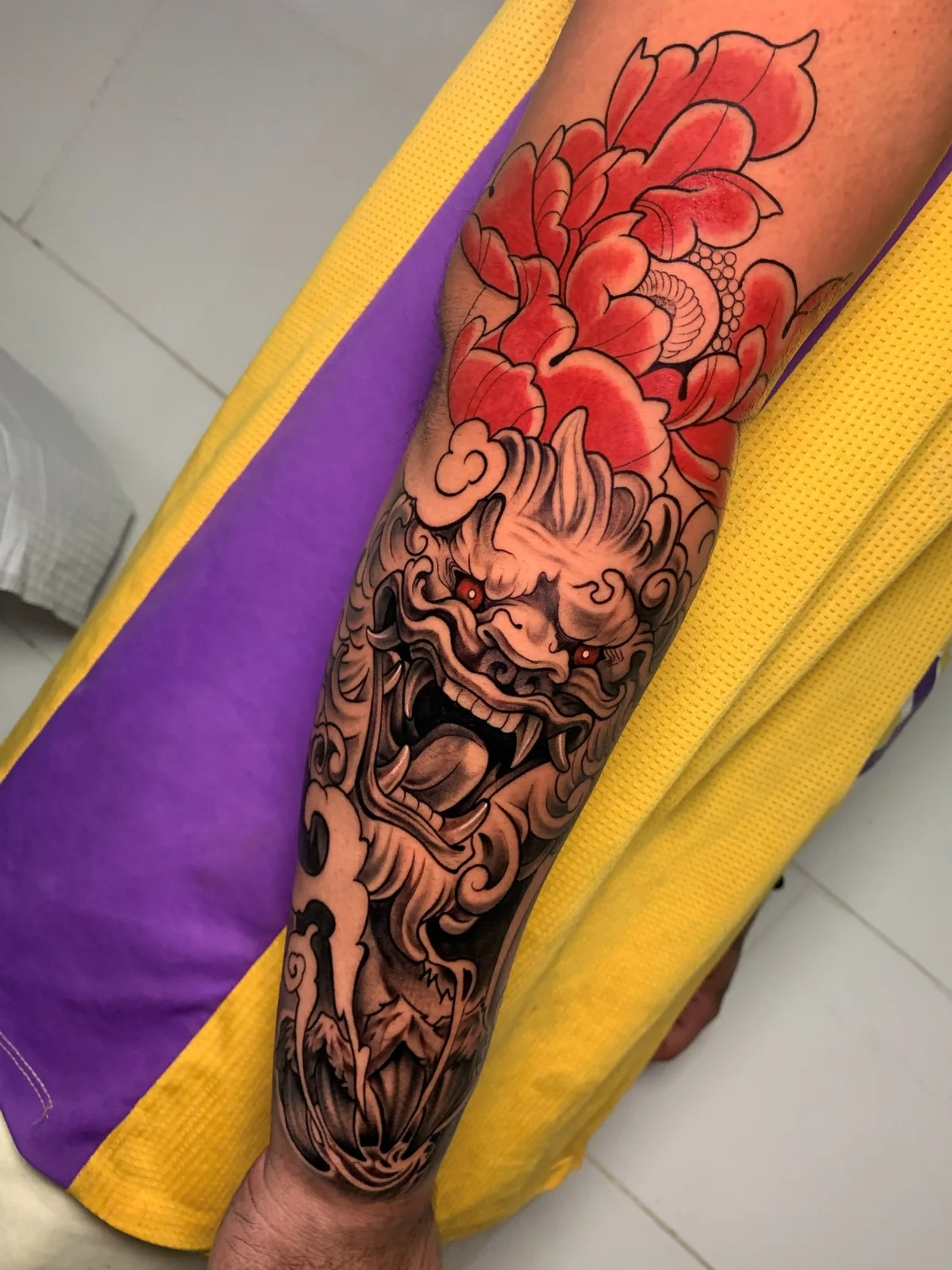 Tatuagem colorida de leão oriental com peônia vermelha na perna