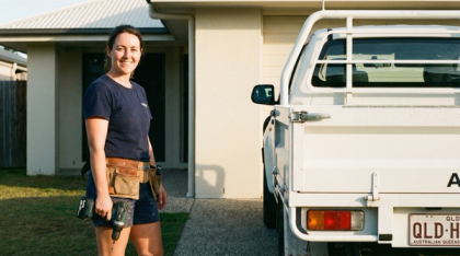 Tradesperson loading equipment beside a utility vehicle