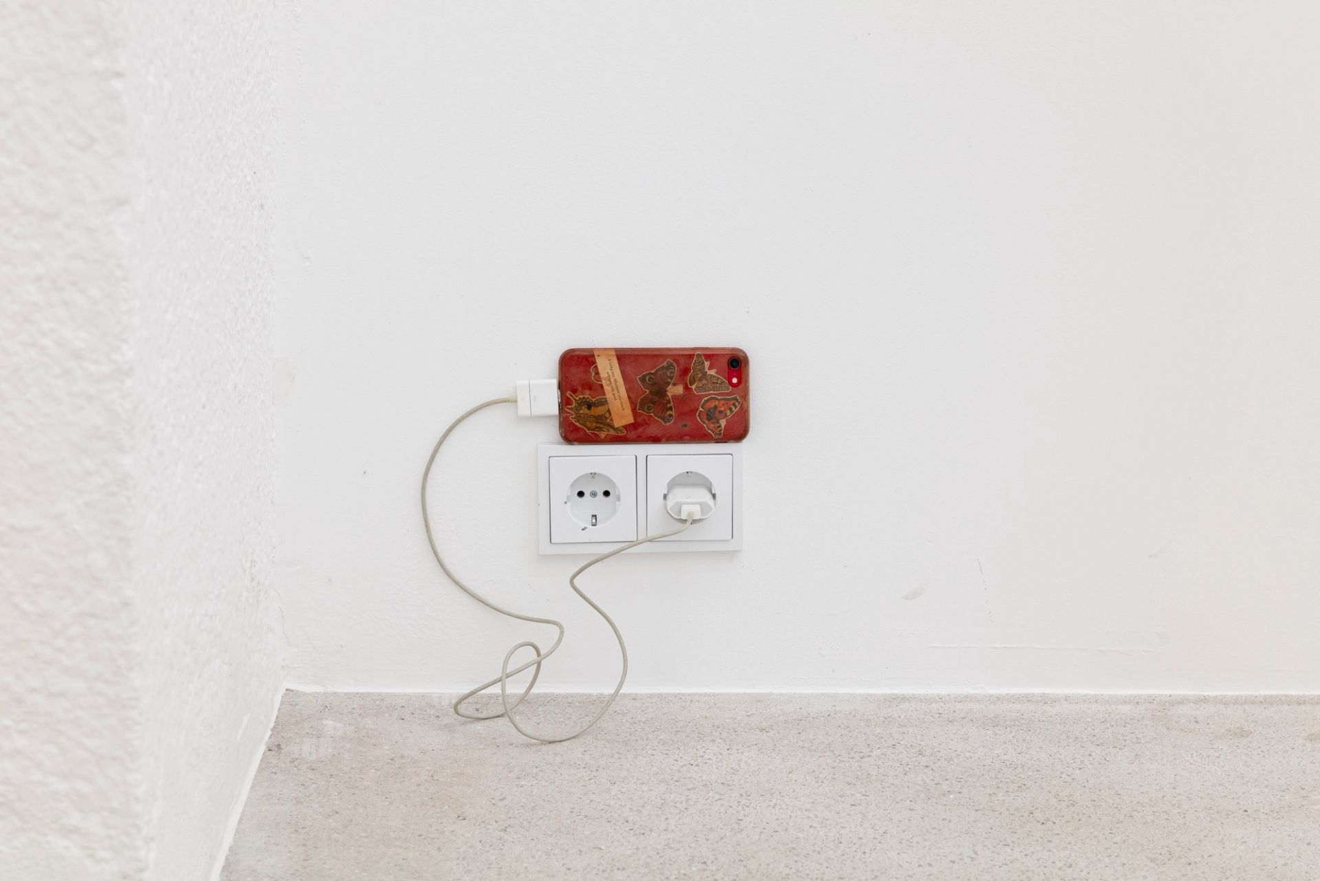 Anna McCarthy, Butterfly Phone, 2025, iPhone, stickers, charger, 13 × 7 × 1 cm, dimensions variable