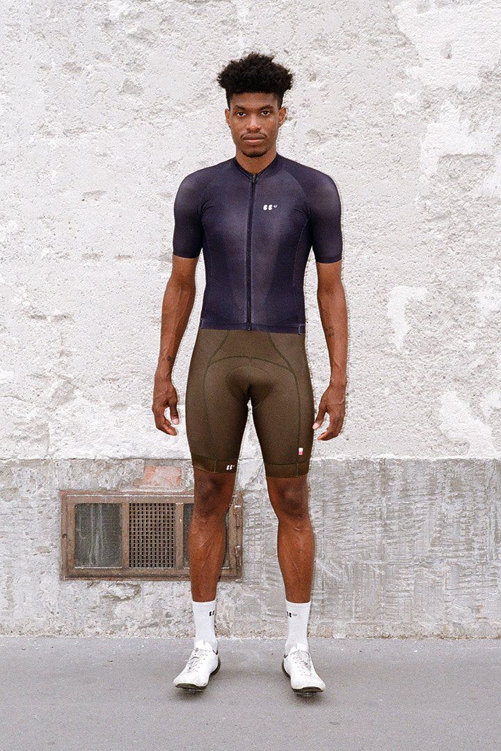 portrait of anthony in front of a concrete wall, wearing everyday jersey black and dance bibs in olive