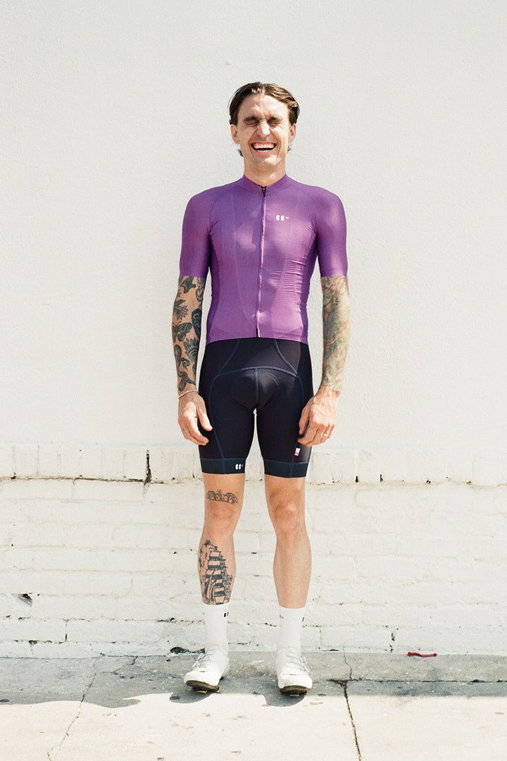 portrait of dylan in front of a white wall, wearing everyday jersey purple and navy dance bibs