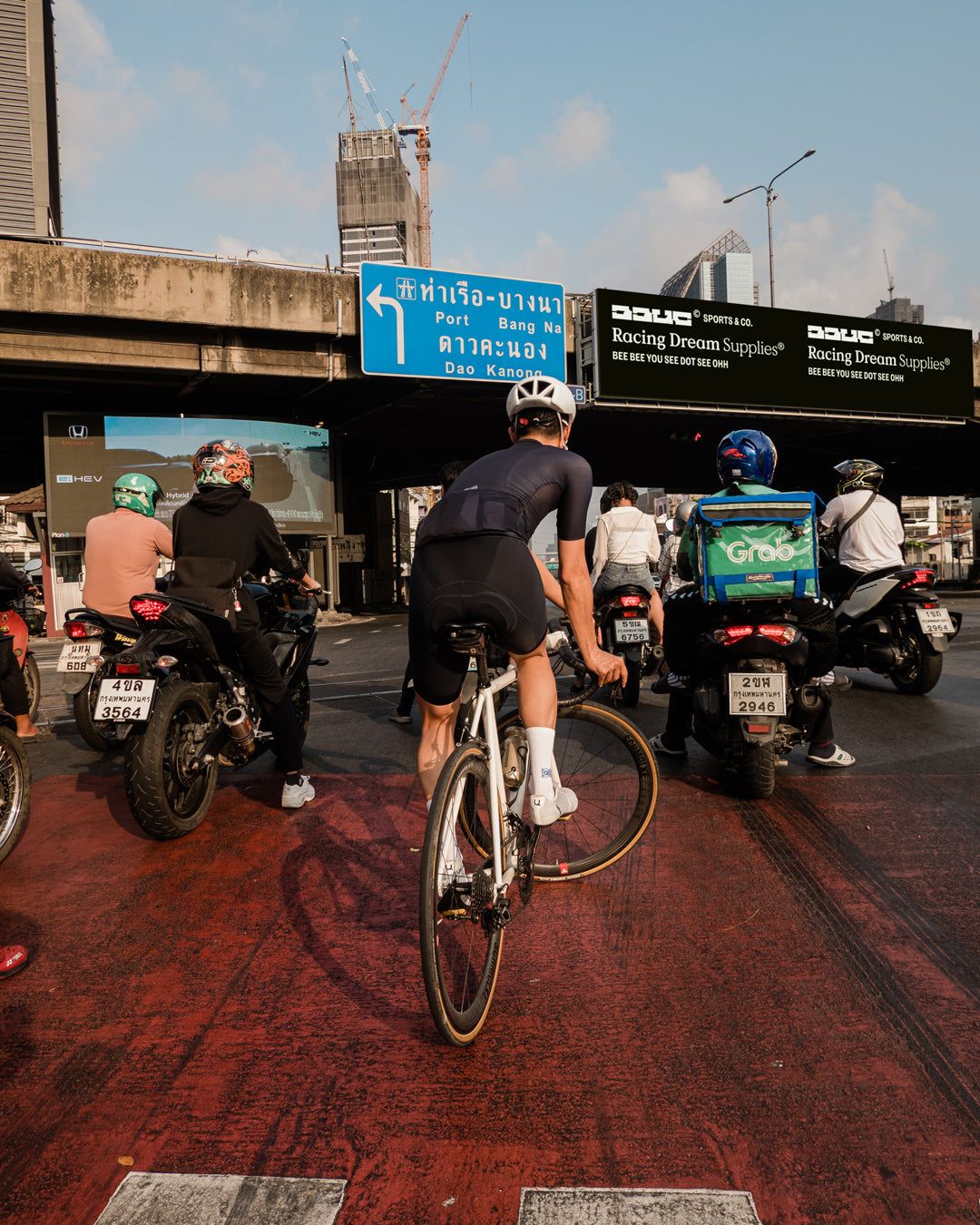 pun trackstanding in bangkok traffic in front of a bbuc advertisement
