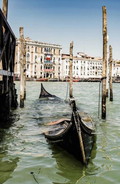 Georgia Ortner Photography sunken black wooden boat and wooden poles in the water and wooden poles with houses in the background
