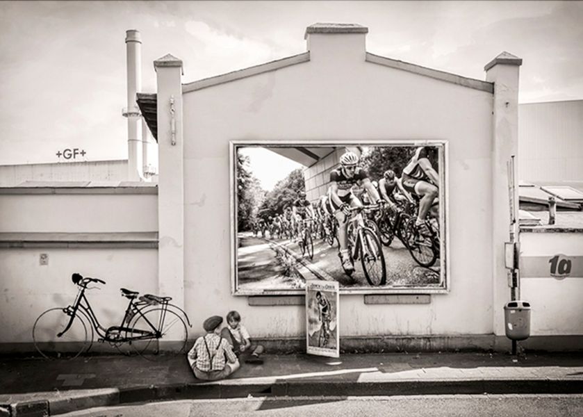 Martina Chardin Fotografie composition schwarzweiß Häuserfront mit Kindern und Fahrrädern und Anzeigetafel Tour de France