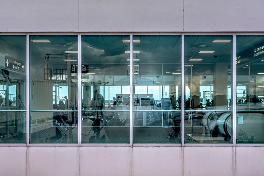 Joe Willems Flughafen Terminal Fensterfront Innenansicht mit Rolltreppe und große Spiegelung eines Flugzeuges