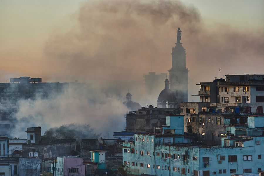 Joe Willems摄影城市景观房屋和教堂塔楼在日落时分哈瓦那的烟云