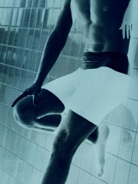 Manfred Vogelsänger abstrakte Fotografie negativ Mann mit Six-pack in Badeshorts im Schwimmbad lehnt an Fliesen