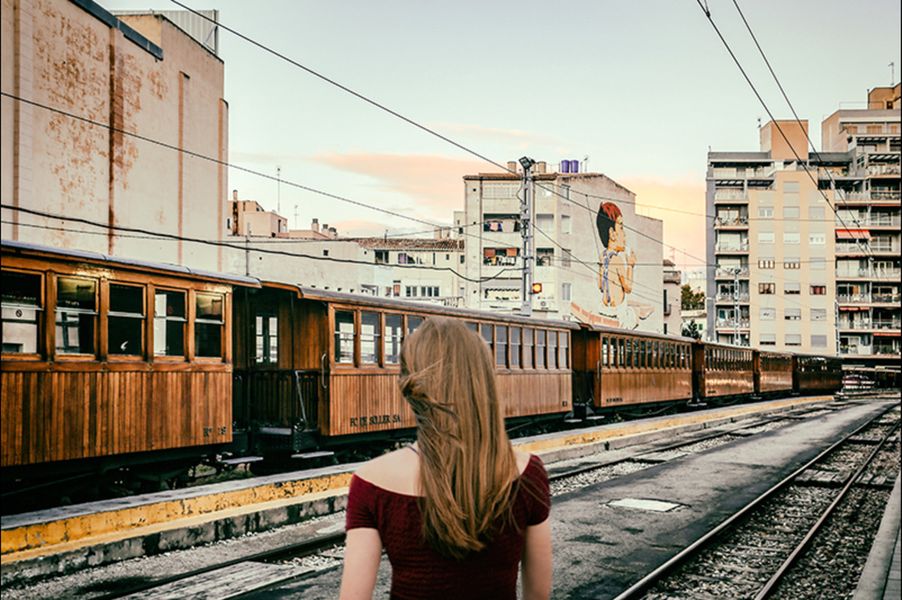 Martina Chardin Fotografie blonde Frau in dunkelrotem Kleid am Bahnschienen in der Stadt