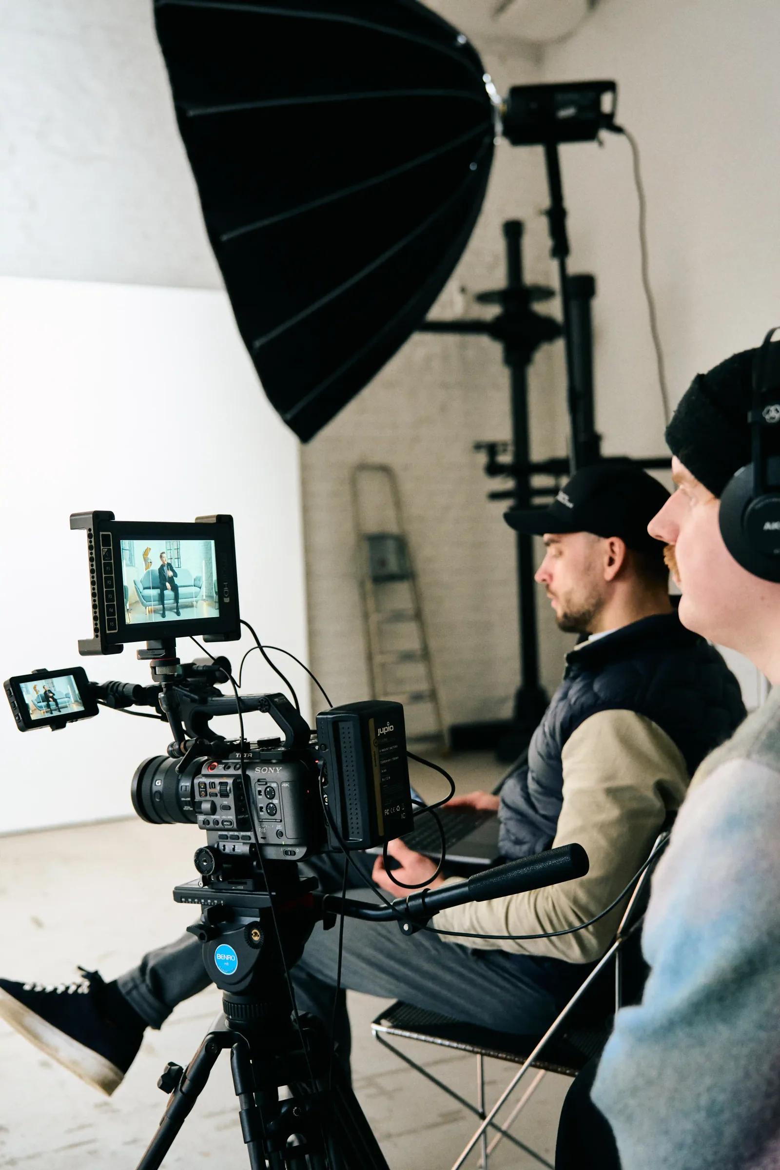Kaameraoperaator ja režissöör filmivad intervjuud valgusküllases fotostuudios