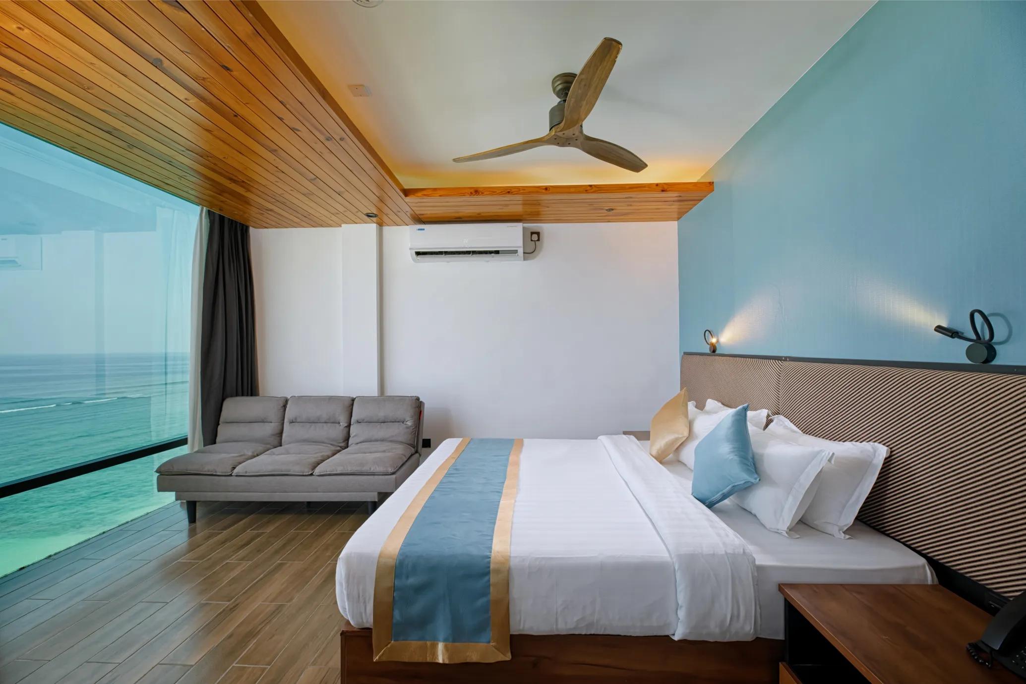Ocean View Suite at h78 Veli with a king bed, sofa and a full-width window over the turquoise sea