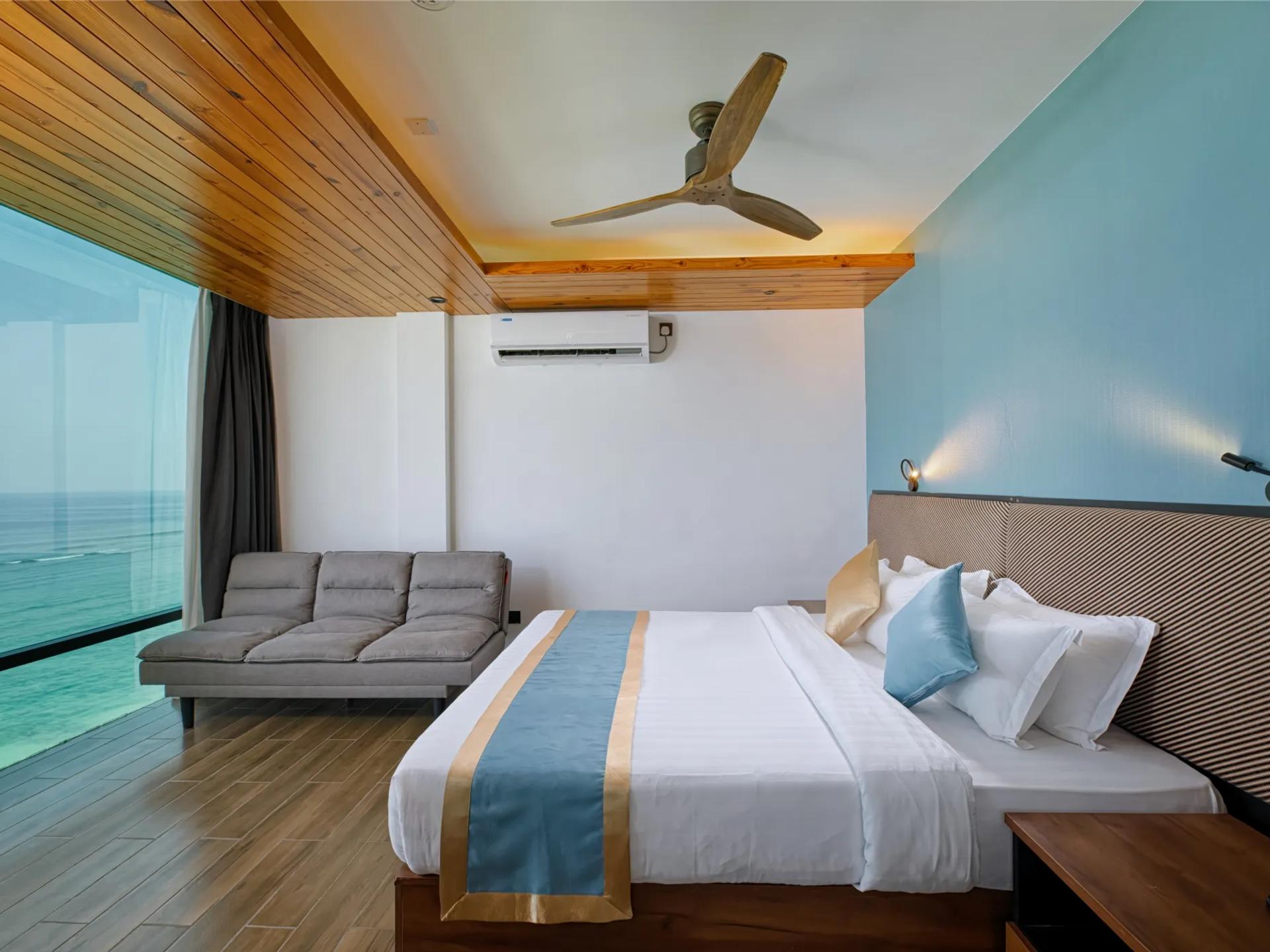 Ocean View Suite at h78 Veli with a king bed, sofa and a full-width window over the turquoise sea