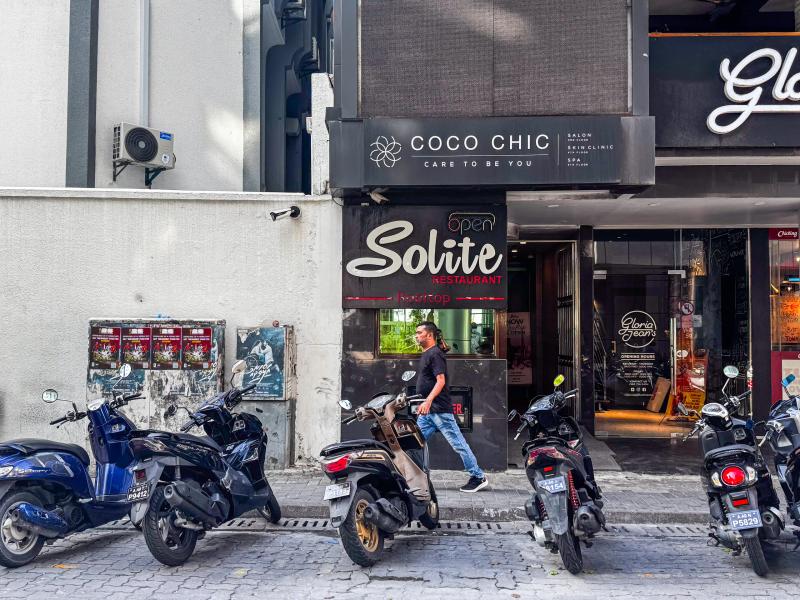 Solite Restaurant's entrance sign with a neon Open light at street level, below the Coco Chic building