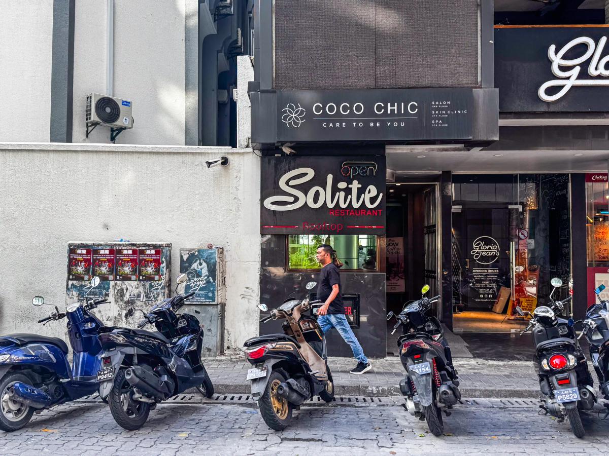 Solite Restaurant's entrance sign with a neon Open light at street level, below the Coco Chic building