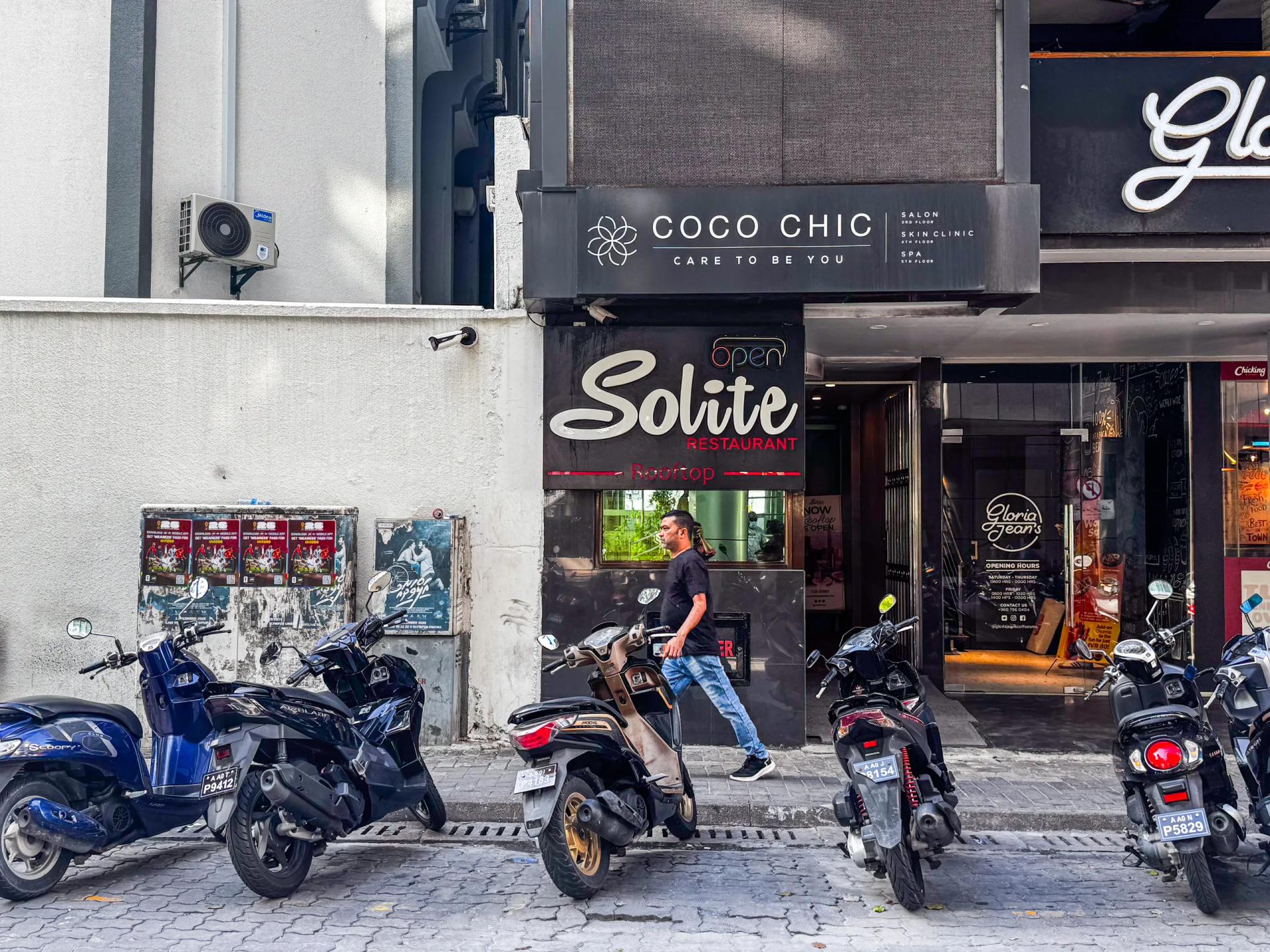 Solite Restaurant's entrance sign with a neon Open light at street level, below the Coco Chic building