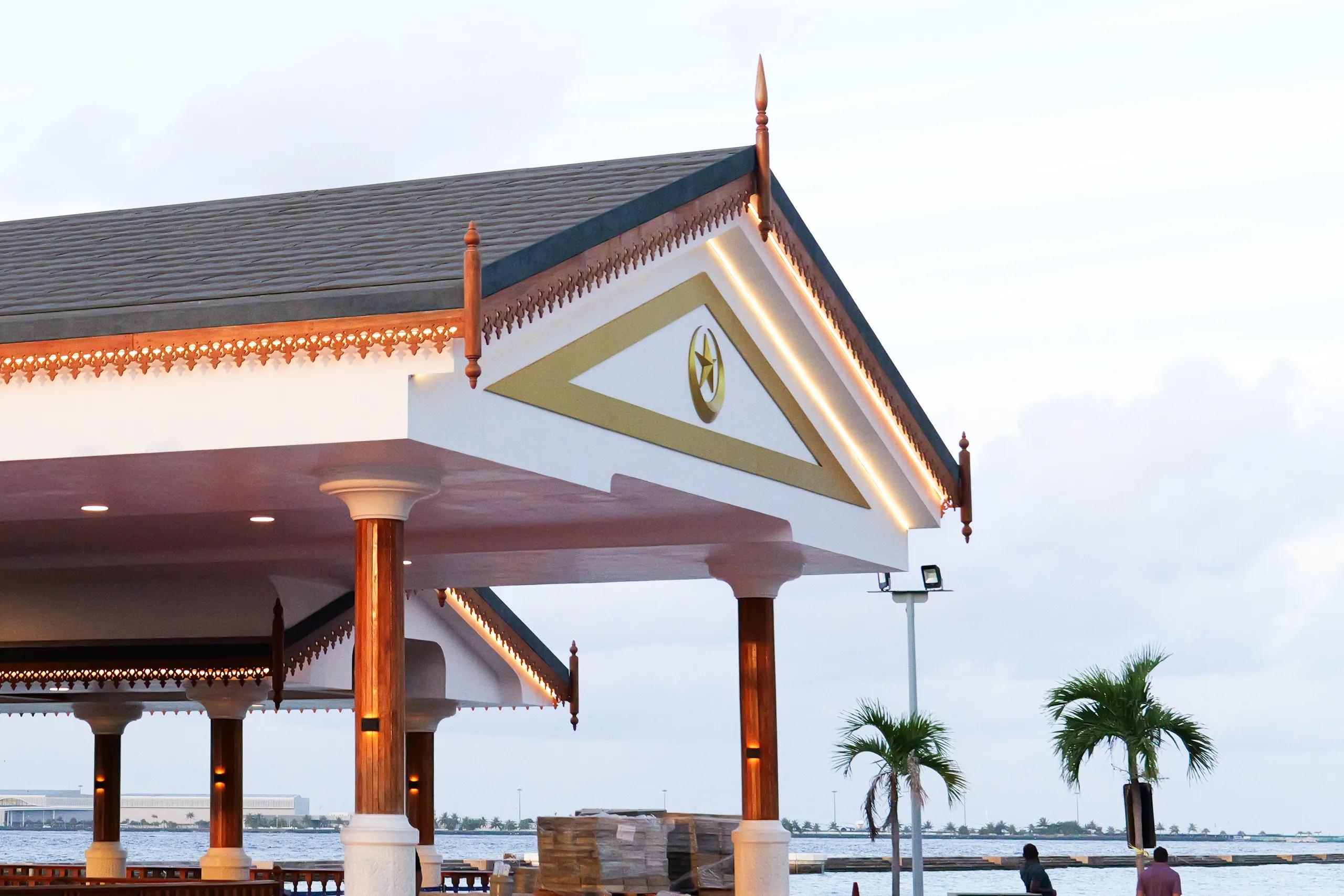 The Presidential Jetty pavilion in Malé, white with carved timber detailing and a gold crescent and star on its gable