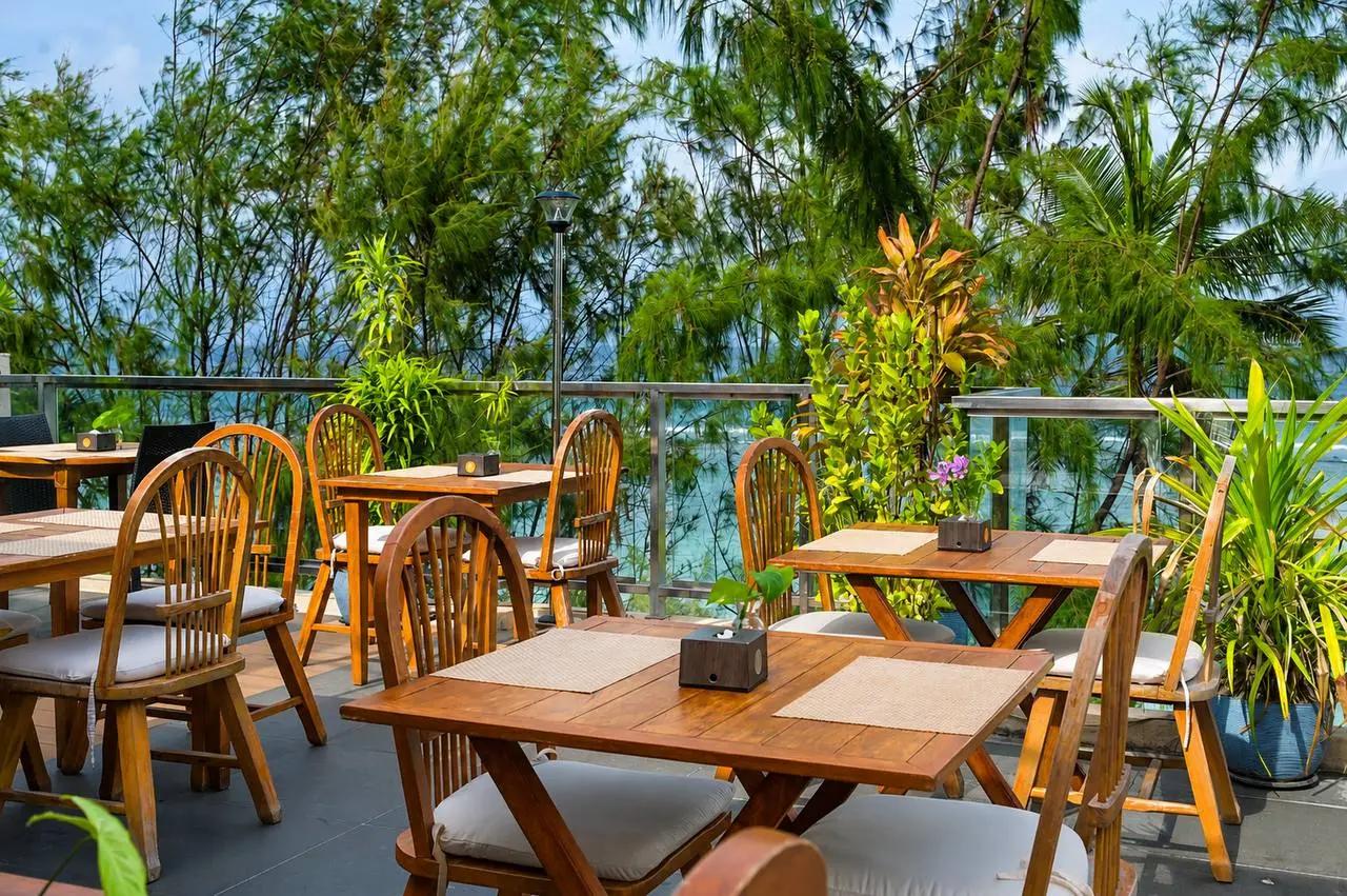 High Tide Restaurant's open-air timber dining terrace at Seasalter Maldives, with wooden tables overseeing the beach