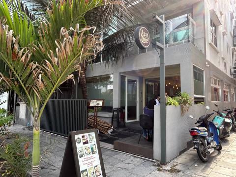 Grey Keylime restaurant with a round logo sign, sidewalk menu board and a palm tree out front