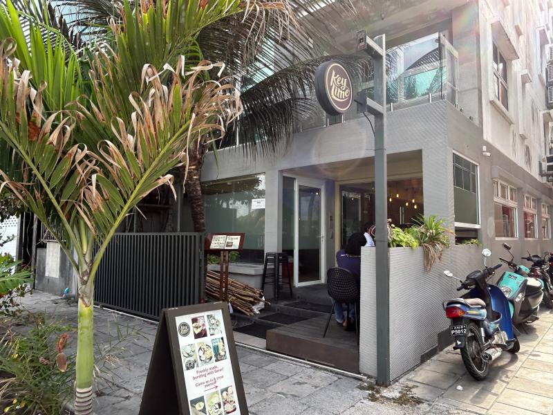 Grey Keylime restaurant with a round logo sign, sidewalk menu board and a palm tree out front