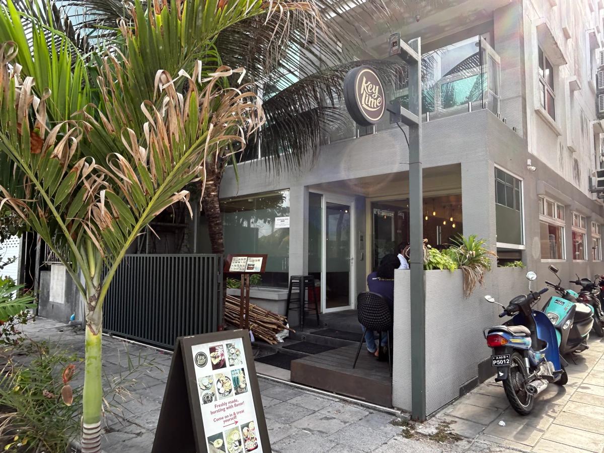 Grey Keylime restaurant with a round logo sign, sidewalk menu board and a palm tree out front