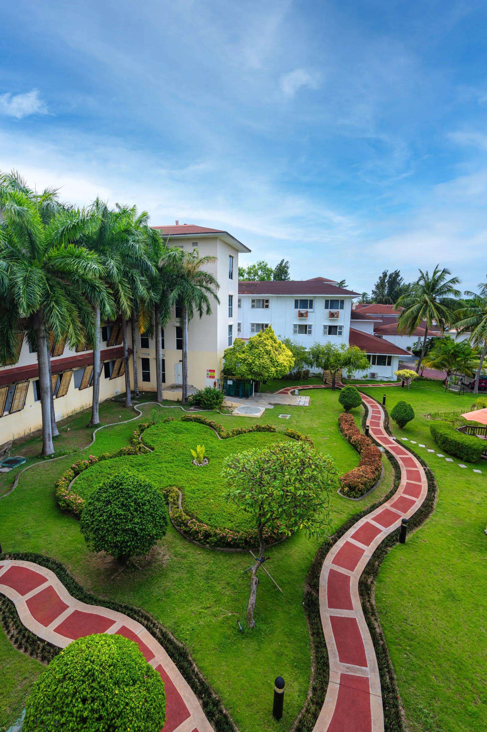 Exterior view of the Hulhule Island Hotel buildings with red-tiled roofs and landscaped garden paths on Hulhule, Maldives.