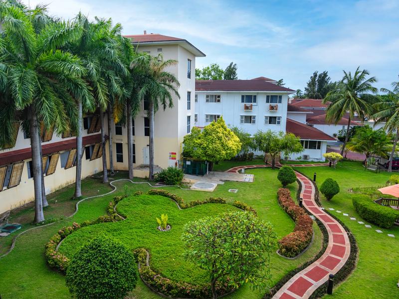 Exterior view of the Hulhule Island Hotel buildings with red-tiled roofs and landscaped garden paths on Hulhule, Maldives.