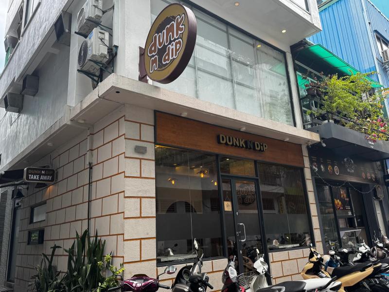 Dunk N Dip's corner storefront with a round logo sign, brick-tiled facade and scooters parked outside