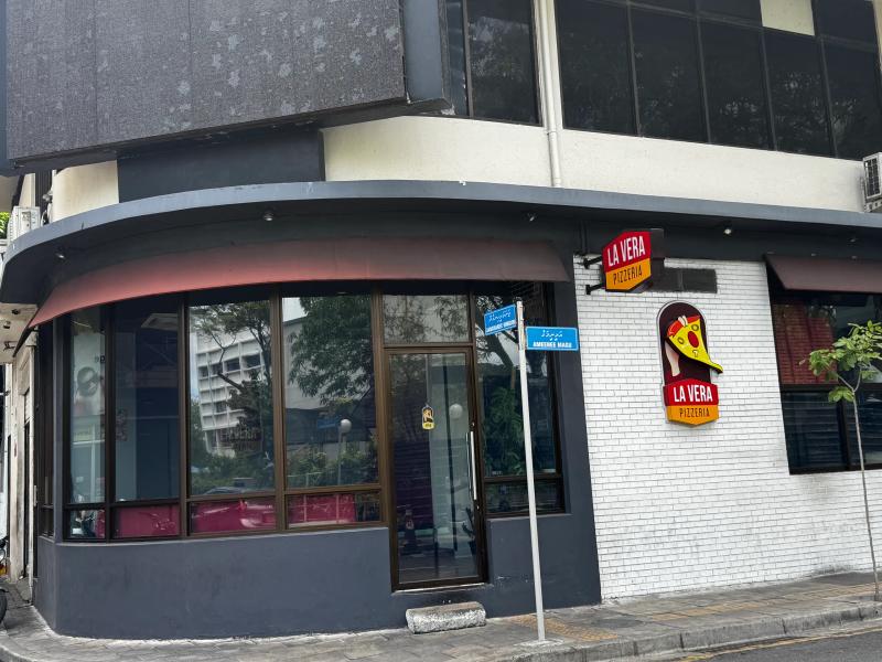La Vera Pizzeria corner unit with a red logo sign and street signs reading Ameenee Magu on a Malé corner