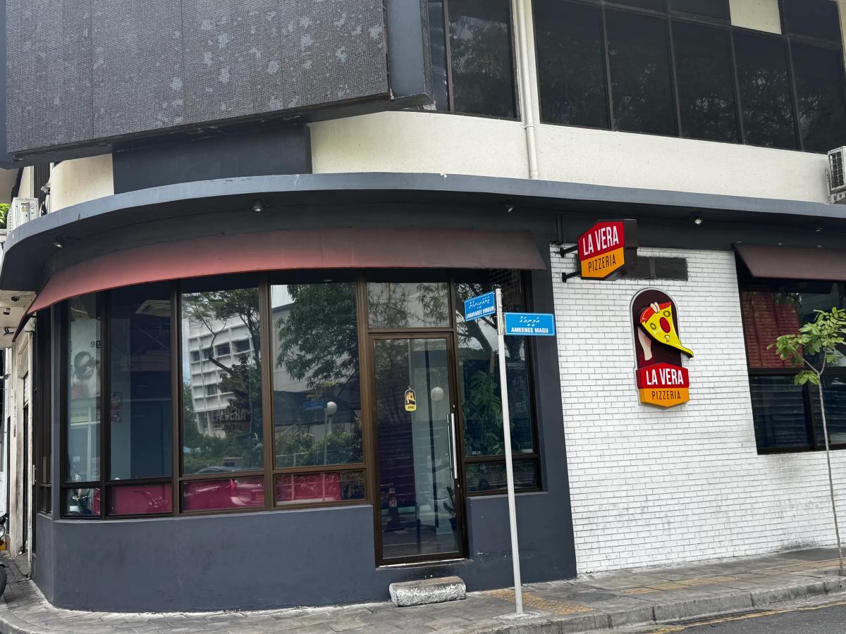 La Vera Pizzeria corner unit with a red logo sign and street signs reading Ameenee Magu on a Malé corner