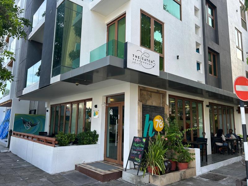The Catch 78 Restaurant in a white building, with a manta ray mural, potted plants and a chalkboard menu