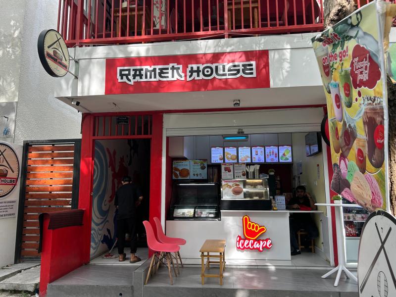 Ramen House open counter with menu screens, an Icecape ice cream display and red chairs at street level