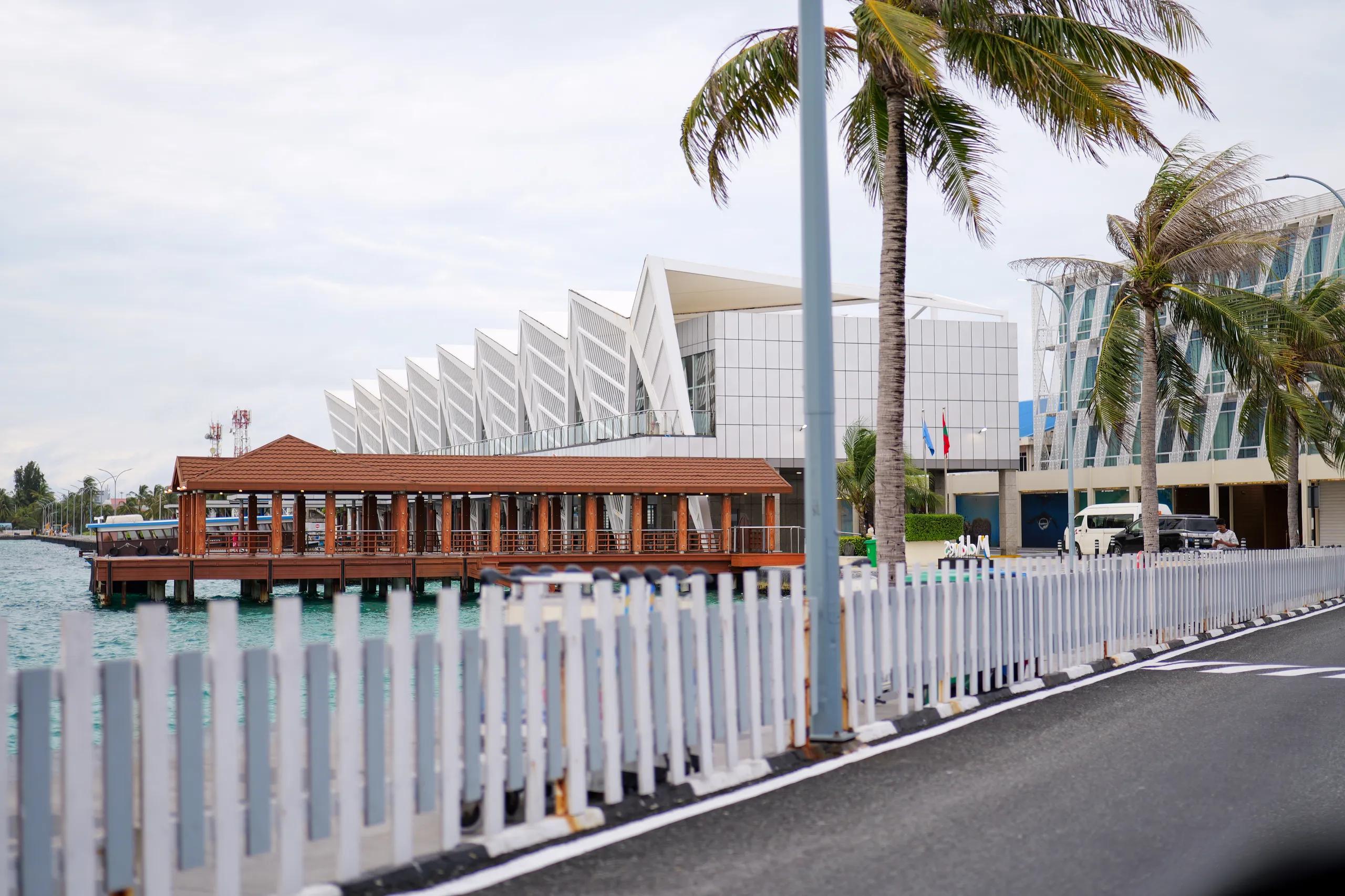 Waterfront walkway at Velana International Airport with the terminal behind