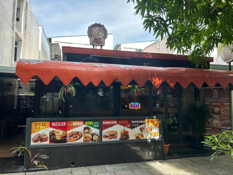 Meat Street with a bull-head logo sign, a red scalloped canopy and menu boards for steak, mandi and burgers