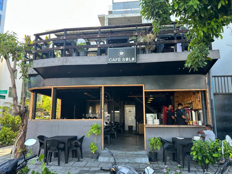 Café Solo's black two-storey timber building with a rooftop terrace and open service counter below