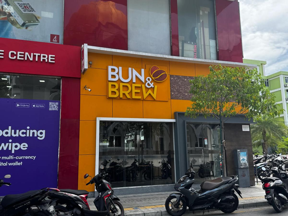 Bun & Brew's orange facade with bold yellow lettering above tinted street-front windows