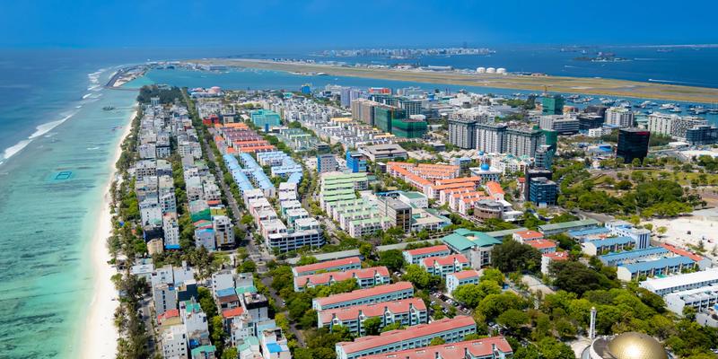 Aerial view of Hulhumalé's long beach and housing blocks, with Malé on the horizon