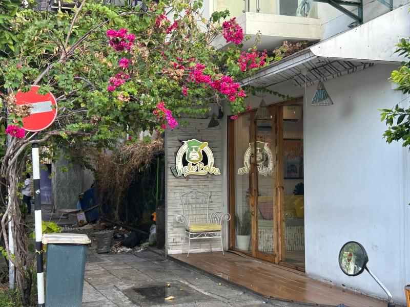 Uncle Bobo entrance with circular logo sign and glass doors framed by pink bougainvillea blooms