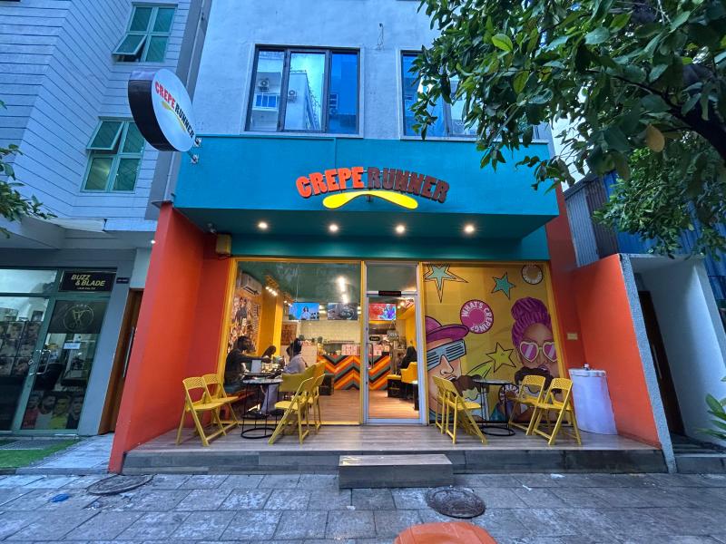 Crepe Runner's teal and orange storefront with yellow chairs and a colourful mural inside