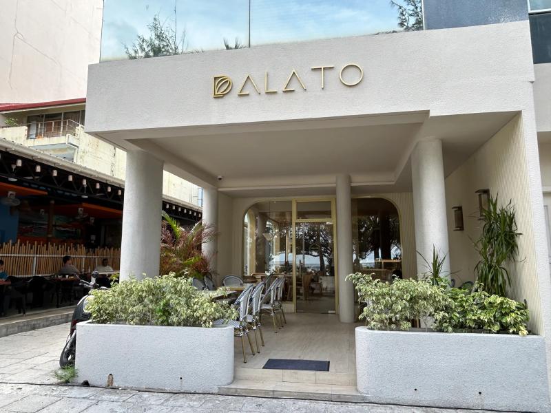 Cream columned entrance of Palato with outdoor bistro chairs and potted plants framing the doorway