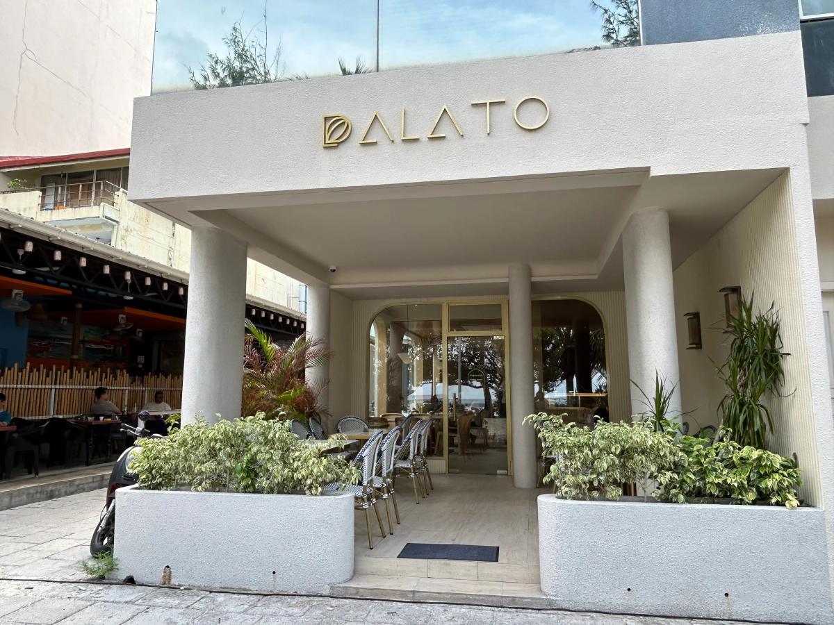 Cream columned entrance of Palato with outdoor bistro chairs and potted plants framing the doorway
