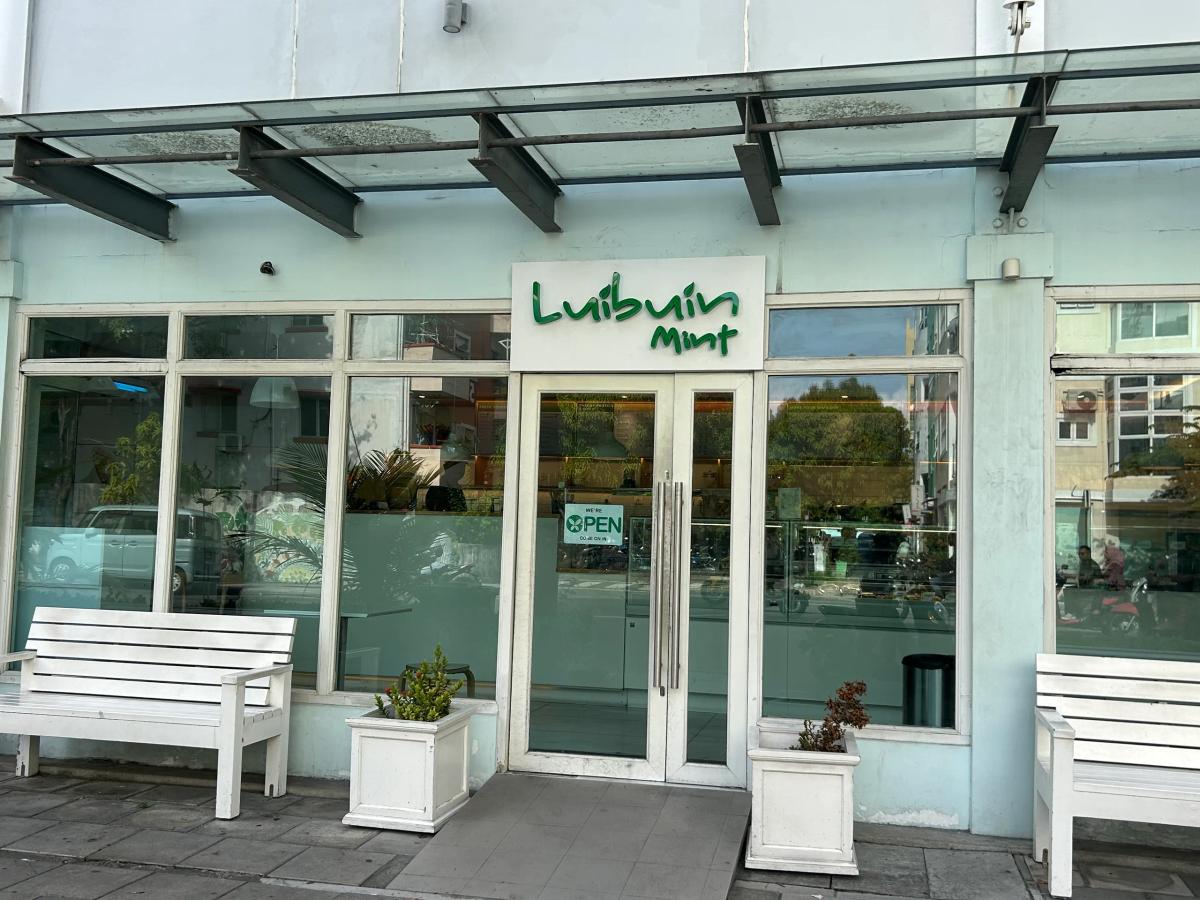 Luibuin Mint cafe storefront in pale mint, with glass doors, large windows, white benches and planters outside