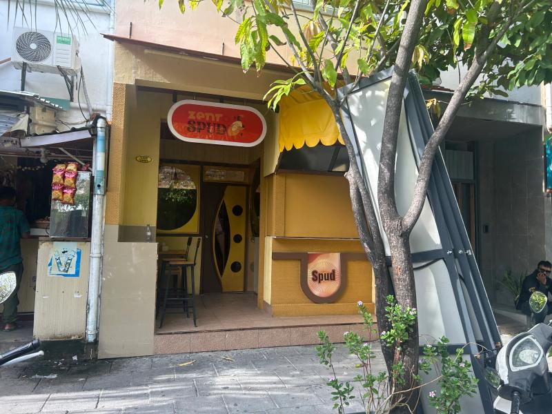Small yellow Ze.NR Spud shopfront with stool seating inside and a Spud sign by the entrance