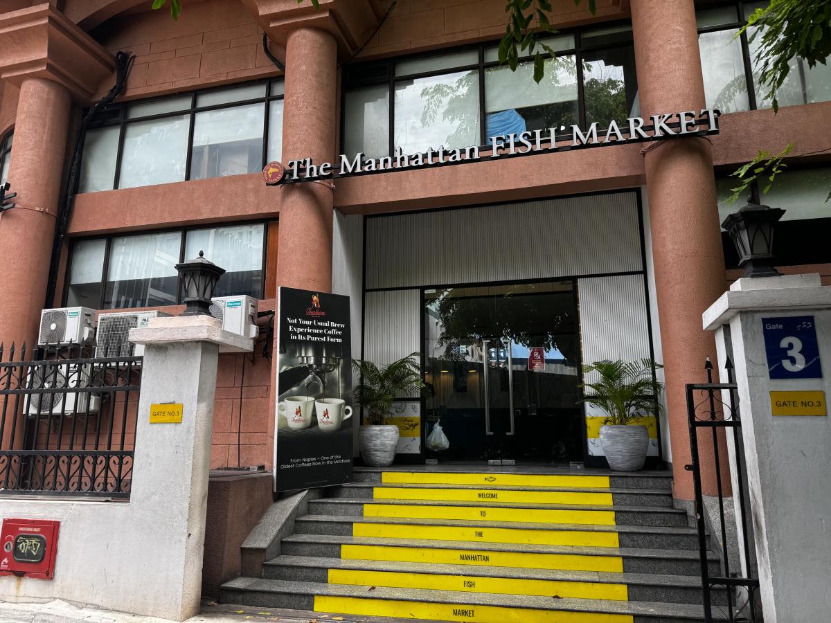 The Manhattan Fish Market entrance with raised columns and yellow stairs lettered Welcome To The Manhattan Fish Market